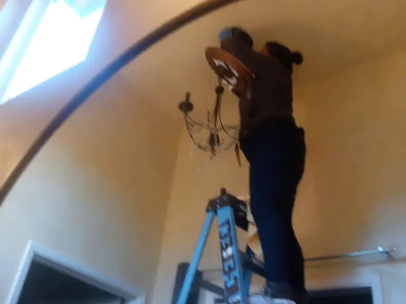 Electrician installing a chandelier in a Geneva residence